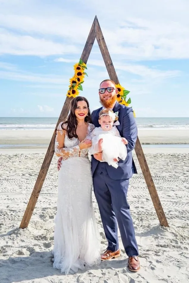 Jesse, owner of Southtech Electric, standing on the beach with his wife and baby on his wedding day